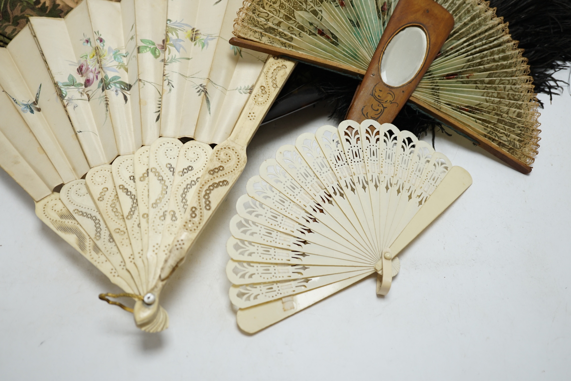 A black ostrich feather and tortoiseshell fan and four others including a carved bone and floral painted silk example. Condition - poor to fair